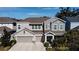 Two-story house with gray siding, three-car garage, and landscaped yard at 5709 Camila Song Ln, Tampa, FL 33625