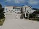 Two-story house with gray siding, three-car garage, and landscaped yard at 5709 Camila Song Ln, Tampa, FL 33625