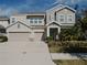 Two-story house with gray siding, three-car garage, and landscaped yard at 5709 Camila Song Ln, Tampa, FL 33625