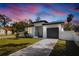 Modern house exterior at dusk, gray garage door at 7909 N 12Th St, Tampa, FL 33604