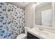 Clean bathroom with a floral shower curtain, modern vanity, and mirrored medicine cabinet at 9626 Charlesberg Dr, Tampa, FL 33635