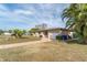 Single-story home with a beige exterior, white garage, and palm trees in the yard at 1004 Orlando Ave, Bradenton, FL 34207