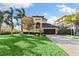 Two-story house with a tan facade, a large garage door, and a nicely landscaped lawn at 110 Driftwood Ln, Largo, FL 33770