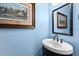 Small powder room with pedestal sink and framed art at 110 Driftwood Ln, Largo, FL 33770