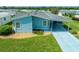 An aerial view of a light blue manufactured home with a carport and landscaping at 37622 New Horizons Blvd, Zephyrhills, FL 33541