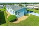 An aerial view of a light blue manufactured home with a carport and landscaping at 37622 New Horizons Blvd, Zephyrhills, FL 33541