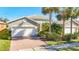Single story home with a two-car garage, brick driveway and palm trees at 15724 Aurora Lake Cir, Wimauma, FL 33598