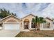 Tan house with palm tree, double doors, and a two-car garage at 1833 Hillcrest St, Tarpon Springs, FL 34689