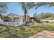 Green backyard featuring pool with safety fence, covered patio, lush plants, and well-maintained lawn at 4829 W San Miguel St, Tampa, FL 33629