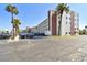 Exterior view of the condo complex with a parking area and lush tropical landscaping at 5575 Gulf Blvd # 425, St Pete Beach, FL 33706