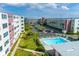 An aerial view of the community pool, parking, and the condo building on a sunny day at 5575 Gulf Blvd # 425, St Pete Beach, FL 33706