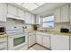 Cozy kitchen area boasts white appliances, bright countertops, and a window with a view at 5575 Gulf Blvd # 425, St Pete Beach, FL 33706