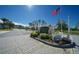 Entrance to Whispering Pines Village, featuring a brick sign and landscaping at 11440 Baronwood Ct, Hudson, FL 34667