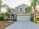 Two-story house with beige exterior, stone accents, and a two-car garage at 12211 Oak Ramble Dr, Spring Hill, FL 34610