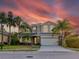 Two-story house with a stone facade, two-car garage, and palm trees at 12211 Oak Ramble Dr, Spring Hill, FL 34610