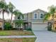Two-story house with beige exterior, stone accents, and a two-car garage at 12211 Oak Ramble Dr, Spring Hill, FL 34610