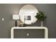 Modern entryway with a white console table, large round mirror, and stylish decor at 15233 Rainbow Quartz St, Wimauma, FL 33598