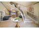 Grand foyer with winding staircase, piano, travertine floor, and elegant chandelier at 26 Sunset Bay Drive, Belleair, FL 33756