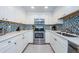 Modern kitchen with white cabinets, stainless steel appliances, and mosaic backsplash at 2700 Bayshore Blvd # 11302, Dunedin, FL 34698