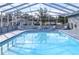 Community pool with screened enclosure and lounge chairs at 37347 Derbyshire Dr, Zephyrhills, FL 33542
