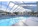 Community pool with screened enclosure and lounge chairs at 37347 Derbyshire Dr, Zephyrhills, FL 33542