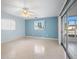 Blue bedroom with ceiling fan, window and sliding glass doors at 713 Gran Kaymen Way, Apollo Beach, FL 33572
