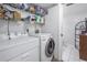 White washer and dryer in a well-lit laundry room with storage shelves at 8954 Antigua Dr, Seminole, FL 33777