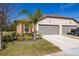 Tan house with gray two-car garage, landscaping, and a truck parked in driveway at 13987 Weddington Ter, Hudson, FL 34669