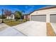 Tan house with gray two-car garage, landscaping, and driveway at 13987 Weddington Ter, Hudson, FL 34669