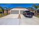Tan house with gray three-car garage, landscaping, and a truck parked in driveway at 13987 Weddington Ter, Hudson, FL 34669