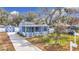 Charming blue house with a white picket fence, landscaping, and a long driveway at 1447 Santa Anna Dr, Dunedin, FL 34698
