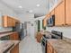 Galley kitchen with stainless steel appliances and light wood cabinets at 2309 Cross Tee Ct, Brooksville, FL 34604