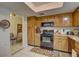 Kitchen boasts wood cabinets, black appliances, and views into adjacent dining area at 2579 Bay Berry Dr # 42D, Clearwater, FL 33763