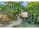 Secluded beach access path marked with private property and no trespassing sign, surrounded by tropical vegetation at 3110 W De Bazan Ave, St Pete Beach, FL 33706