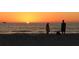 Tranquil beach scene featuring a colorful sunset, silhouetted figures, and calm ocean waters at 3110 W De Bazan Ave, St Pete Beach, FL 33706