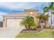 Tan house with two-car garage, landscaping, and palm trees at 6206 Windship Ct, Tampa, FL 33647
