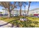 Well-maintained condo building with green trim, a sign, mature trees, and dedicated parking spaces at 2468 Florentine Way # 52, Clearwater, FL 33763
