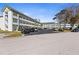 Exterior view of a condo building with dedicated parking, landscaped grounds, and mature trees at 2468 Florentine Way # 52, Clearwater, FL 33763