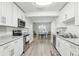 Open concept kitchen with white cabinets, granite countertops, and stainless steel appliances at 1732 Flamingo Ln, Sun City Center, FL 33573