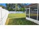 Backyard with grass, screened patio, and white fence at 4119 Harrisburg Ne St, St Petersburg, FL 33703