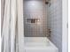 Modern bathroom with gray tile, shower/tub combo, and linen curtain at 519 Loquat Dr, Anna Maria, FL 34216
