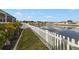 Backyard featuring a white picket fence lining a large pond with lush tropical foliage at 7320 Newhall Pass Ln, Wesley Chapel, FL 33545