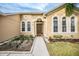 Tan house exterior with a walkway leading to the front door, nicely landscaped at 13029 Haverhill Dr, Spring Hill, FL 34609