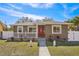 Updated bungalow exterior, featuring a red door, white fence, and landscaping at 4318 1St S Ave, St Petersburg, FL 33711
