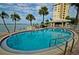 Relaxing kidney-shaped pool with palm trees and building in background at 4725 Cove Cir # 211, St Petersburg, FL 33708