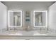 Double vanity bathroom with LED backlit mirrors, a decorative wall accent, and modern fixtures at 725 Capri Blvd, Treasure Island, FL 33706