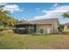Backyard featuring a sunroom, landscaping, and green grass at 10704 Mira Vista Dr, Port Richey, FL 34668