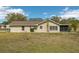 Tan house exterior with a screened patio and grassy yard at 10704 Mira Vista Dr, Port Richey, FL 34668