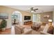 Staged living room with hardwood floors, ceiling fan, arched doorways, and open dining area, promoting comfortable living at 10704 Mira Vista Dr, Port Richey, FL 34668