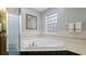 Luxurious bathroom highlighting corner tub with glass block window and shower with glass door at 1712 Blind Pond Ave, Lutz, FL 33549